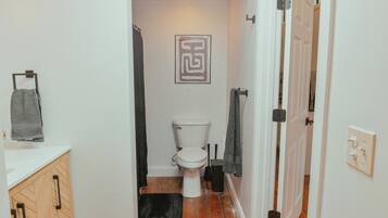 Un baño estrecho con un inodoro, un perchero y una cortina de ducha.