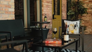 A cozy outdoor seating area with a table, chairs, and a basket of bottles. - Large Condo in the heart of GR (Grand Rapids)