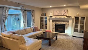A living room with a sofa, a coffee table, a fireplace, and a bookshelf. - Calgary Lake House B&B (Calgary)