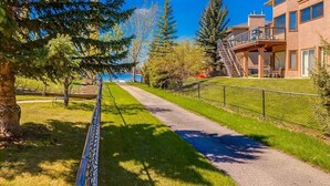 A pathway leading to a building with a balcony, surrounded by trees and a clear sky. - Calgary Lake House B&B (Calgary)