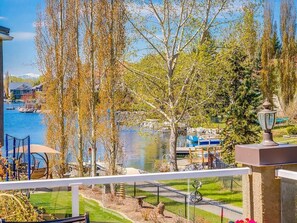 Une vue sur le lac depuis un balcon, avec en arrière-plan un quai, des arbres et un bâtiment.