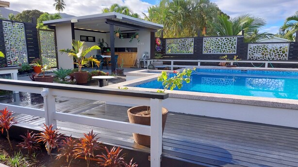 Un espace piscine doté d’un coin salon abrité, de plantes en pot et offrant une vue sur le paysage environnant.