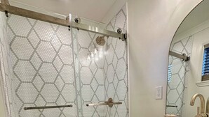 A modern bathroom with a glass shower enclosure, a toilet, and a vanity with a sink and mirror.