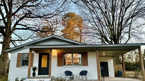 A single-story house with a front porch, two chairs, and a mailbox.