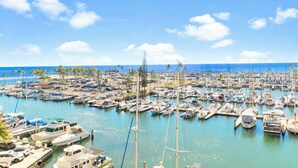 A marina with numerous boats docked, a clear blue sky, and a calm sea.