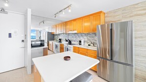 A modern kitchen with wooden cabinets, stainless steel appliances, and a white countertop.