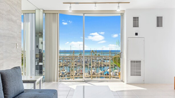 A modern living room with a large sliding glass door leading to a marina view.