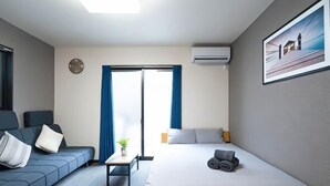 A hotel room with a bed, a sofa, a small table, a clock, and a window with curtains. - Shishinkaku (Kyoto)