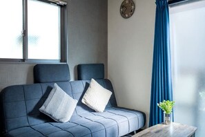 A modern room with a sofa, pillows, a clock, and a window with curtains. - Shishinkaku (Kyoto)