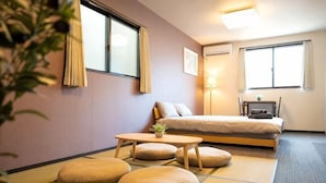 A hotel room with tatami mats, a bed, a table with cushions, and two windows with curtains. - Shishinkaku (Kyoto)