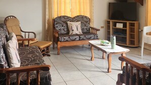 Een woonkamer met een bank, stoelen, een salontafel, een televisie en een airconditioning.
