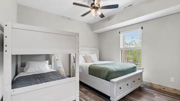 Une chambre avec un lit superposé, un lit simple et un ventilateur de plafond.
