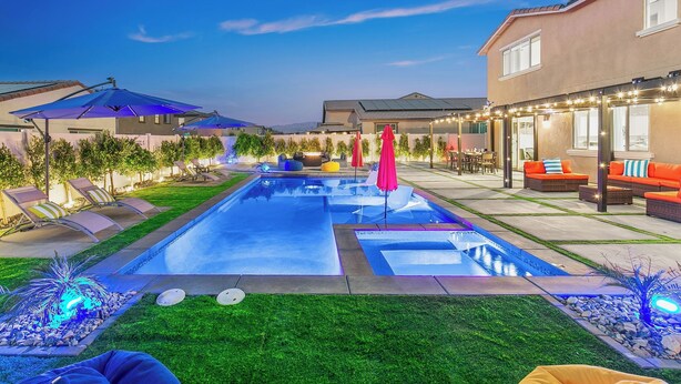 Un jardin avec une piscine, un espace salon extérieur et une maison.