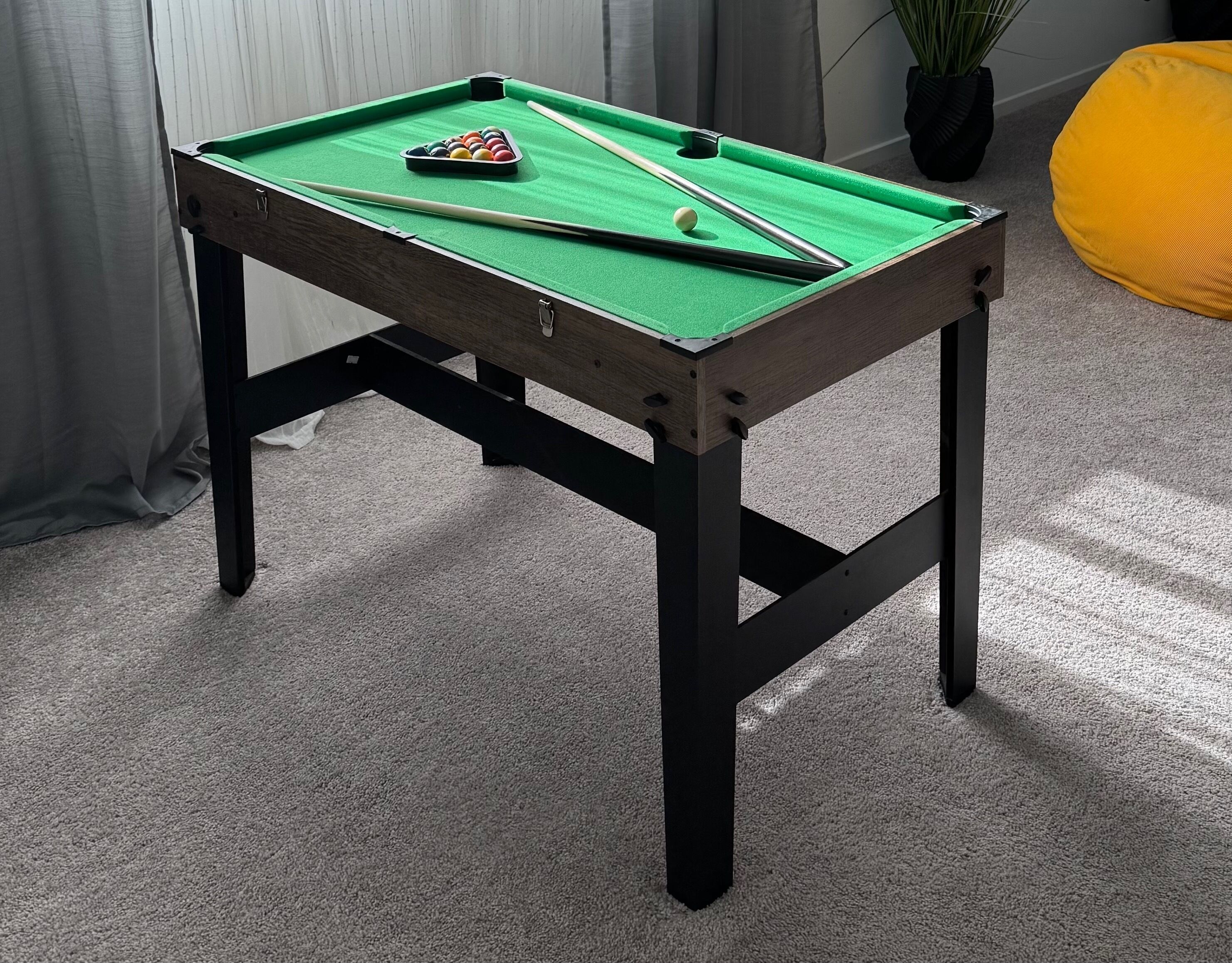 A pool table with a green felt surface, two pool cues, and a set of balls.