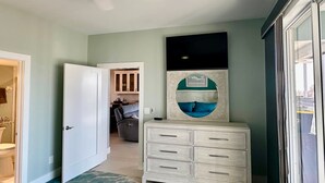 Un couloir avec une commode blanche, une porte donnant sur une salle de bain et une vue sur un espace cuisine.