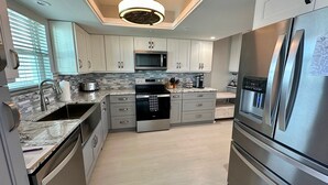 Une cuisine moderne équipée d’appareils électroménagers en acier inoxydable, d’un four à micro-ondes, d’un four et d’un réfrigérateur.
