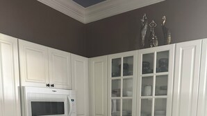 Una cocina con armarios blancos, microondas, estufa y fregadero.