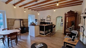 Ampla sala de estar com mesa de jantar, cozinha e vista através de uma grande janela.