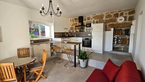 Una cocina moderna con comedor, que presenta una pared de piedra, una araña y un sofá rojo.