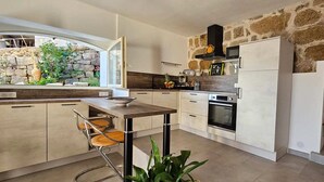 Una cocina moderna con pared de piedra, electrodomésticos integrados y vistas al exterior.