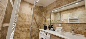 A modern bathroom with a shower, a washing machine, a sink with toiletries, and a mirror. - Beautiful & old renovated T3 apartment in Sartène (Sartène)
