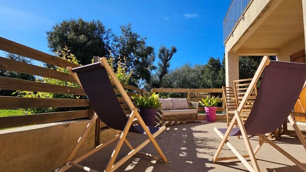 An outdoor seating area with two folding chairs, a sofa, and potted plants.