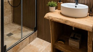 A modern bathroom with a glass-enclosed shower, a wooden vanity with a sink, and a mirror above the vanity.
