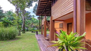 A wooden deck with a staircase leading to a covered porch, surrounded by lush greenery and palm trees. - Beachfront Family Villa with Cook & Daily Cleaning / Great for kids (Puerto Viejo de Talamanca)