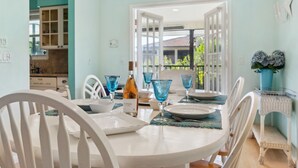 A dining area with a round table, white chairs, and blue glassware. - Green Turtle Boathouse/HOT TUB view of the canal (Naples)
