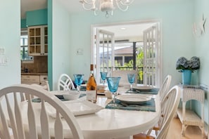 Un coin repas avec une table ronde, des chaises blanches et de la verrerie bleue.