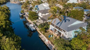 A residential area with houses along a waterway, docks, and a boat. - Green Turtle Boathouse/HOT TUB view of the canal (Naples)