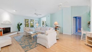 A spacious living room with a fireplace, a sofa, a coffee table, and a ceiling fan. - Green Turtle Boathouse/HOT TUB view of the canal (Naples)