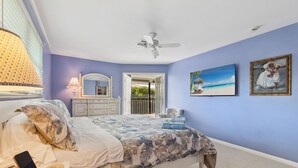 A bedroom with a bed, a ceiling fan, a TV, a dresser, and a door leading outside. - Green Turtle Boathouse/HOT TUB view of the canal (Naples)
