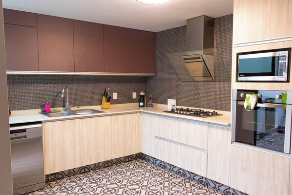 Equipped with a gas stove, microwave, oven, and dishwasher, this kitchen offers a clean and functional layout.