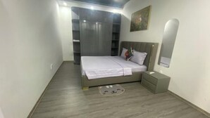 A bedroom with a bed, bedside table, wardrobe, and a mirror on the wall. - 3-bedroom Oasky Vung Tau with Partial Ocean View (Ho Chi Minh City)