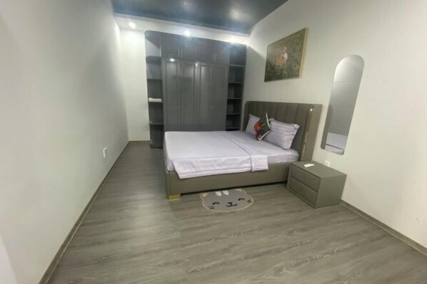 Ein Schlafzimmer mit Bett, Nachttisch, Kleiderschrank und Spiegel.