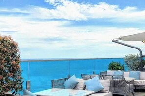 Un espacio al aire libre con vistas al mar, con mobiliario de mimbre y una mesa.