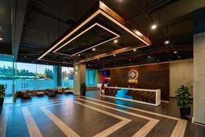 Un área de recepción moderna con mostrador, zona de estar y amplios ventanales.