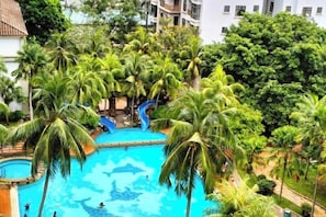 A swimming pool surrounded by palm trees and a building in the background. - Homestay Melaka at Mahkota Hotel - Unit 3093, 2092 - Free Wifi & Parking (Melaka)