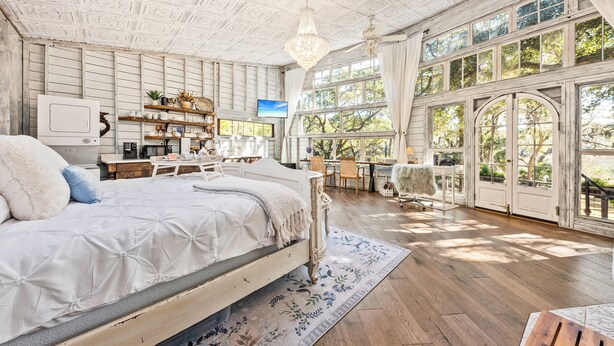 Un dormitorio espacioso con una cama grande, suelo de madera y vistas amplias a través de ventanas grandes.