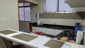 A kitchen with a long counter, two chairs, a sink, and a window. - Orchid farm and beach (Gonzaga Santos)