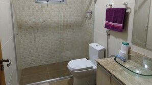 A bathroom with a glass shower enclosure, a toilet, and a sink with a glass countertop. - Orchid farm and beach (Gonzaga Santos)