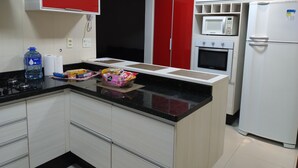 A modern kitchen with a central island, white and red cabinets, a microwave, oven, and a refrigerator. - Orchid farm and beach (Gonzaga Santos)
