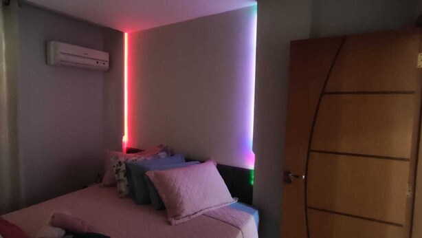 A bedroom with a bed, pillows, a wardrobe, and an air conditioning unit. - Orchid farm and beach (Gonzaga Santos)