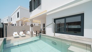 Una piscina moderna al aire libre con sillones de descanso y un área de estar cubierta.