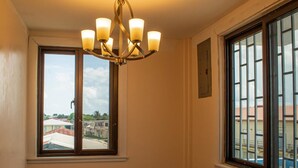 A hotel room with a chandelier, two windows, and a view of buildings outside. - Barana Hotel (Dangriga)
