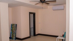 A room with a ceiling fan, an air conditioning unit, a door, and a chair. - Barana Hotel (Dangriga)