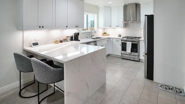 A modern kitchen with white cabinetry, a marble island, two bar stools, a stove, and a refrigerator. - Beautiful & Centrally Located close to everything 3- bedroom home, AC, WiFi (Baldwin Park)