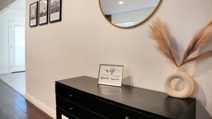 A hallway with a black console table, a framed WiFi password sign, and a mirror on the wall. - Beautiful & Centrally Located close to everything 3- bedroom home, AC, WiFi (Baldwin Park)