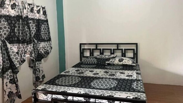 Un dormitorio con cama, cabecera y ventana con cortinas.